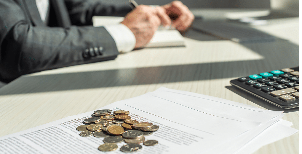 Cropped view of businessman writing in notebook near coins and petitions for bankruptcy on table, on