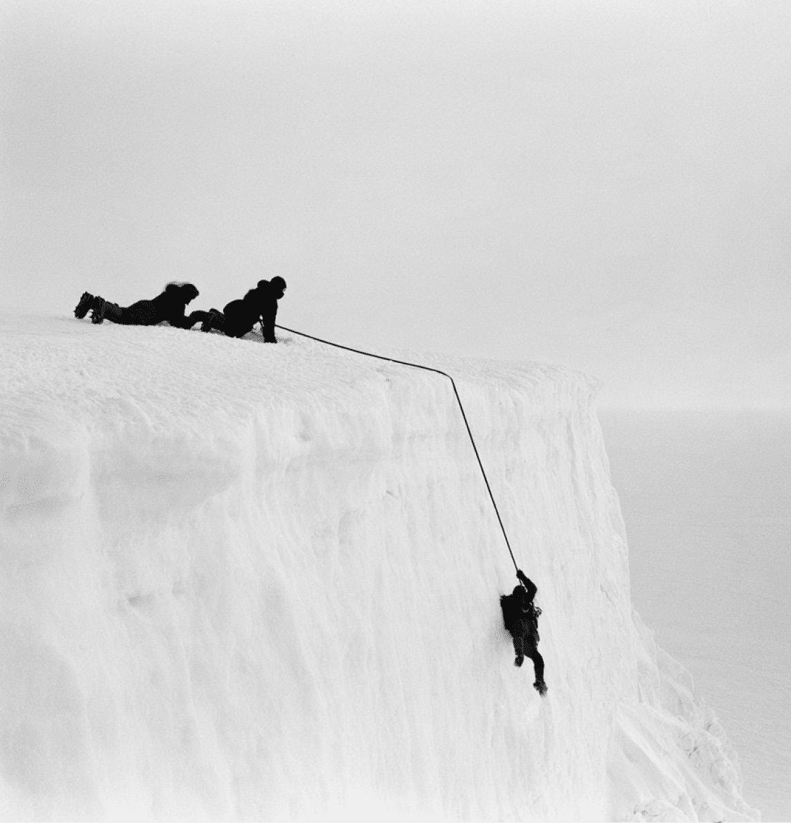 Duas pessoas vestidas com roupas de frio est o em uma atividade de escalada em uma parede de gelo, uma segurando uma corda enquanto a outra sobe. Yapay zeka taraf ndan olu turulan a  klama